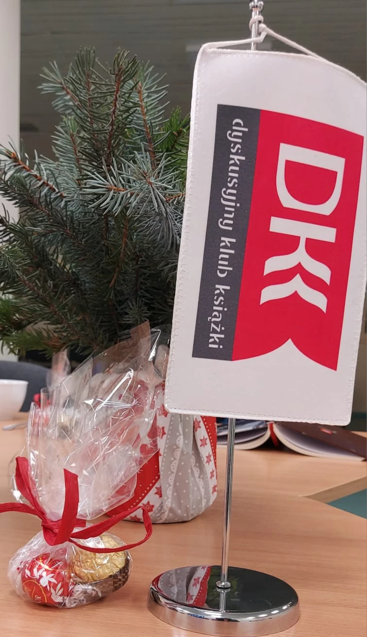 Fotografia przedstawia proporczyk DKK na tle świątecznej choinki.